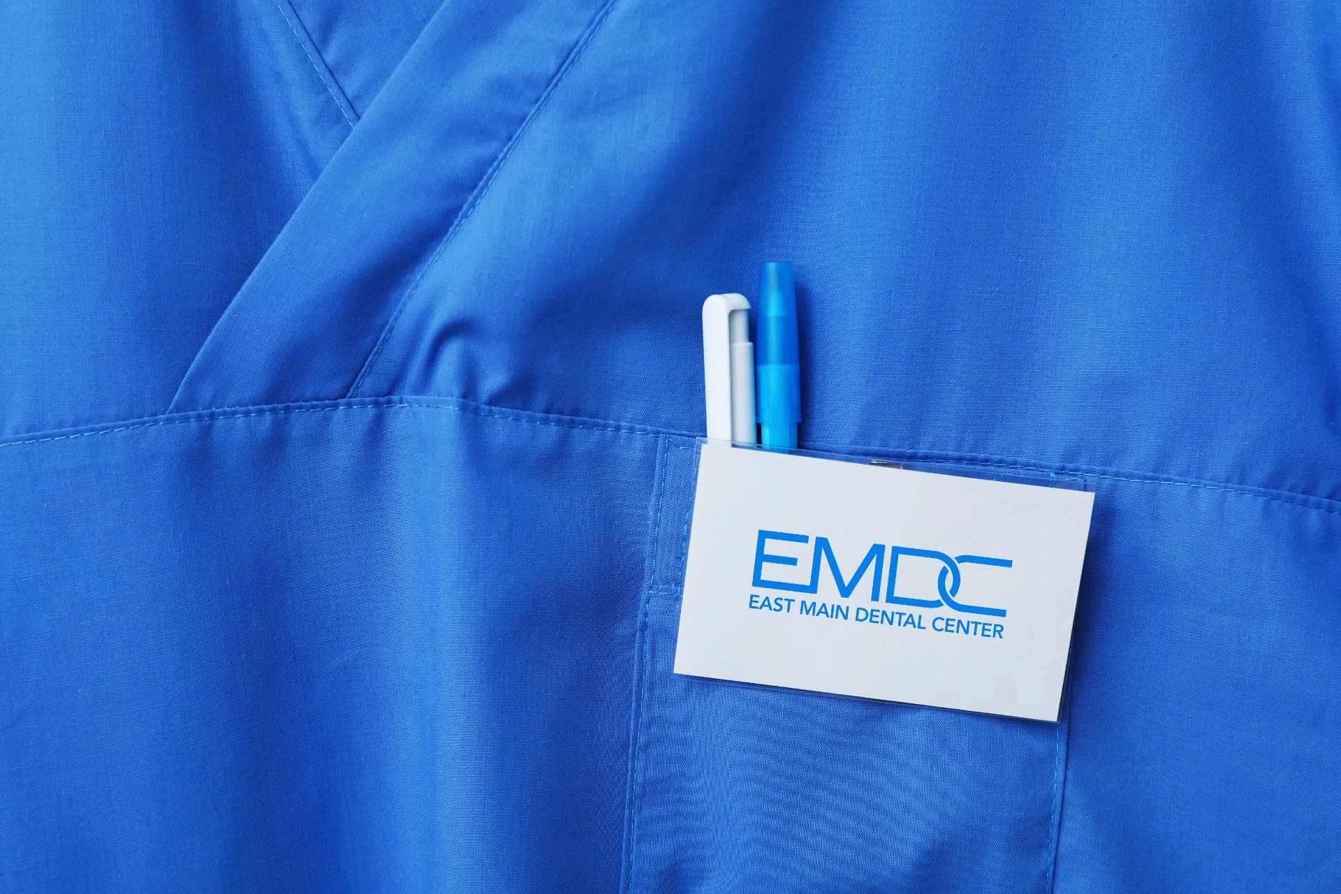 East Main Dental Center branding — EMDC badge on a blue uniform mockup