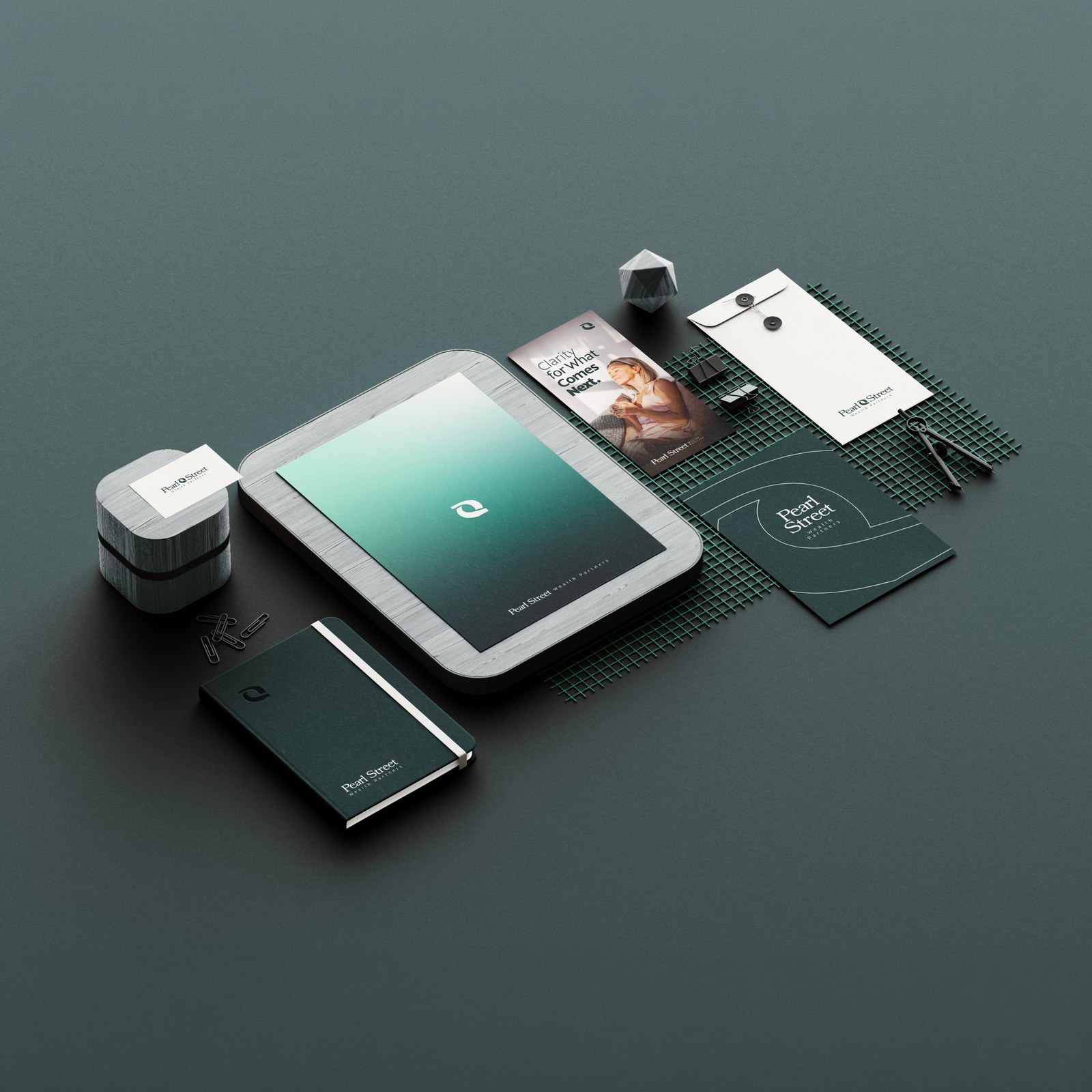 Pearl Street Wealth stationery and brand collateral — brochure tray, notebook, envelope, business cards and desk accessories — arranged on a dark surface