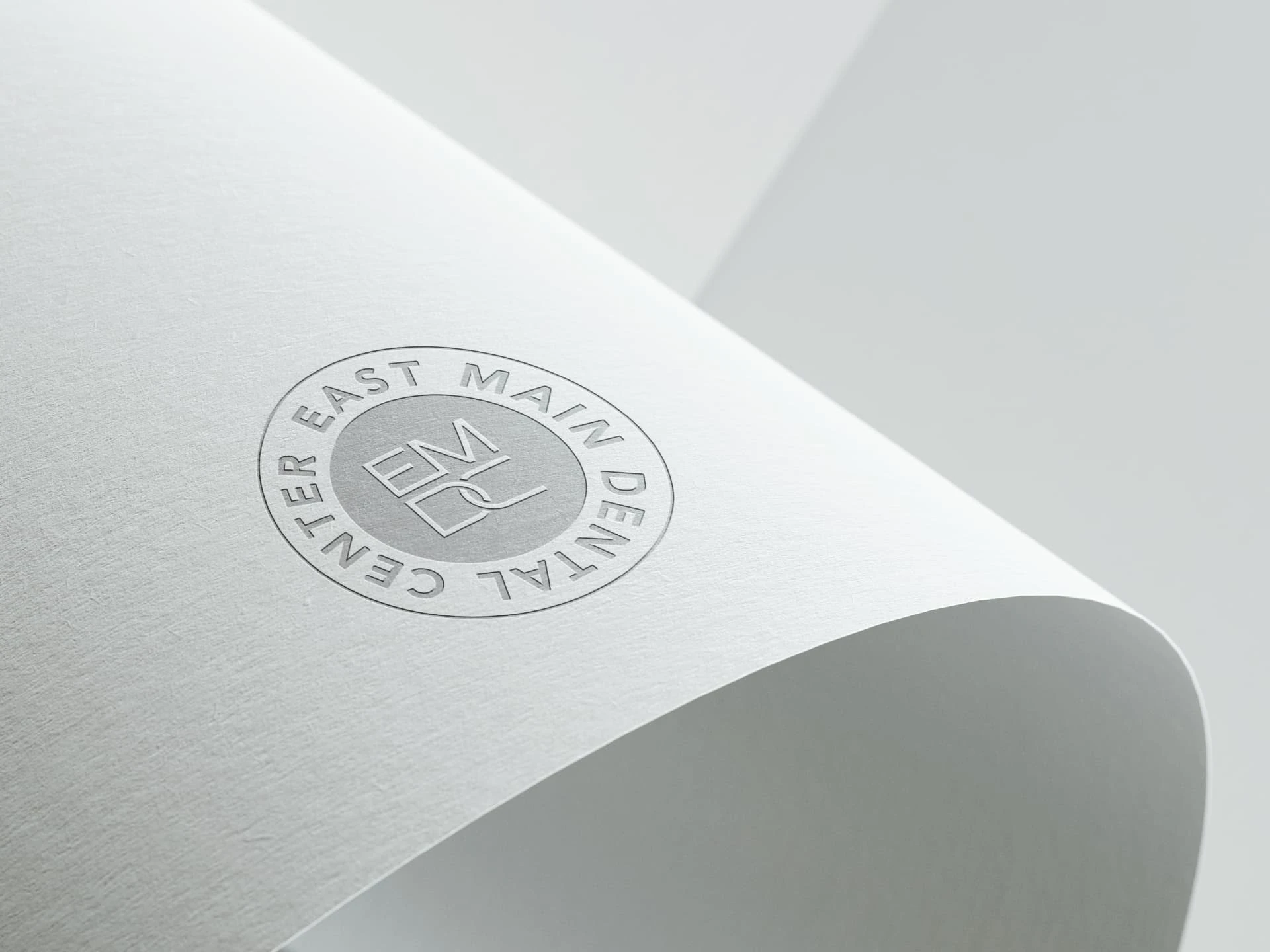 East Main Dental Center identity — circular EMDC seal embossed on paper